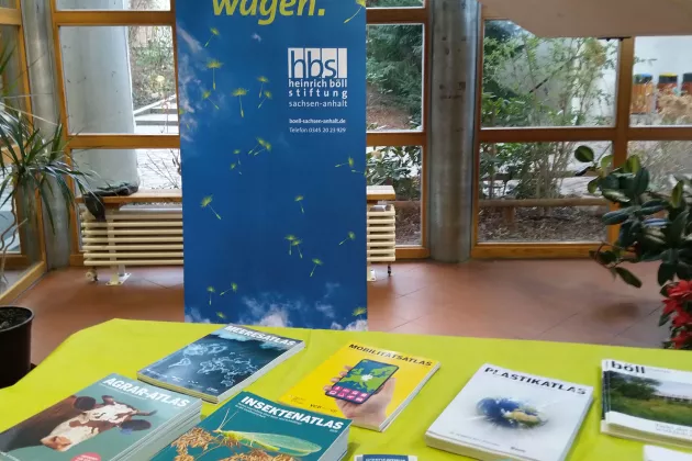 Tisch mit verschiedenen Publikationen, Banner der Stiftung im Hintergrund